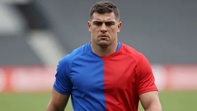 Mid-20s muscular full-back, short dark hair, focused eyes, slight stubble, waist-up portrait in a plain training top...