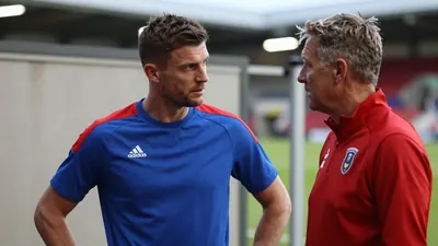 A 35-year-old, 5'11" Premier League midfielder with a rugged build, stands in the tunnel of The Shay Stadium, his face...