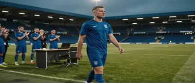 A hyper-realistic editorial sports photo of FC Halifax Town's new goalkeeper Grant, in a plain blue and white unbranded...