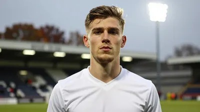 A head-and-shoulders photo of a young, athletic player in FC Halifax Town's kit, wearing a clean white jersey with a...