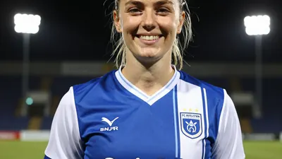 A close-up of Holleigh Farrington, the new club secretary of FC Halifax Town, smiling and wearing the team's blue and...