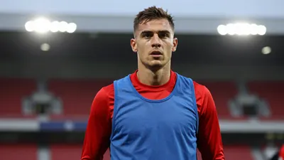Mid-30s Halifax midfielder, athletic build, waist-up, wearing an unmarked training top split blue left side, red right...