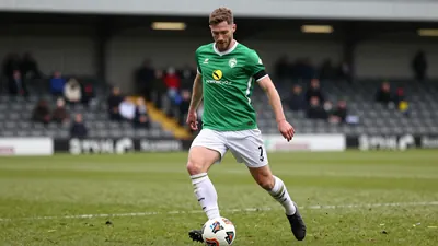 A tight action crop of an anonymous FC Halifax Town player, aged 25-30, in a midfielder role, with a green jersey and...