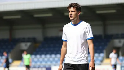 A head-and-shoulders photo of a young, fit-looking defender in the FC Halifax Town kit, wearing a clean white shirt with...
