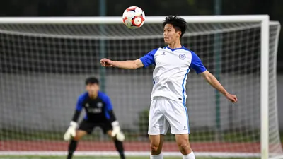 A tight action crop of a young, athletic-looking player in a white and blue kit, with a floodlight rim light and a...