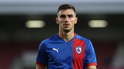 Mid-30s, athletic midfielder, waist-up, intense gaze, short dark hair, light stubble, wearing a plain FC Halifax Town...